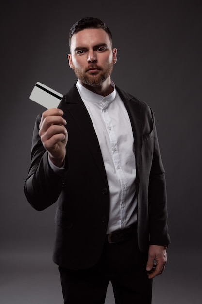 Un hombre elegante con barba sostiene una tarjeta de crédito.