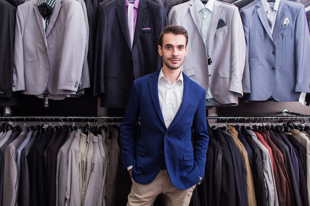 Foto hombre elegante en una boutique de ropa en el fondo de las chaquetas