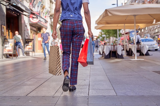 Hombre elegante caminando por la ciudad con bolsas de compras