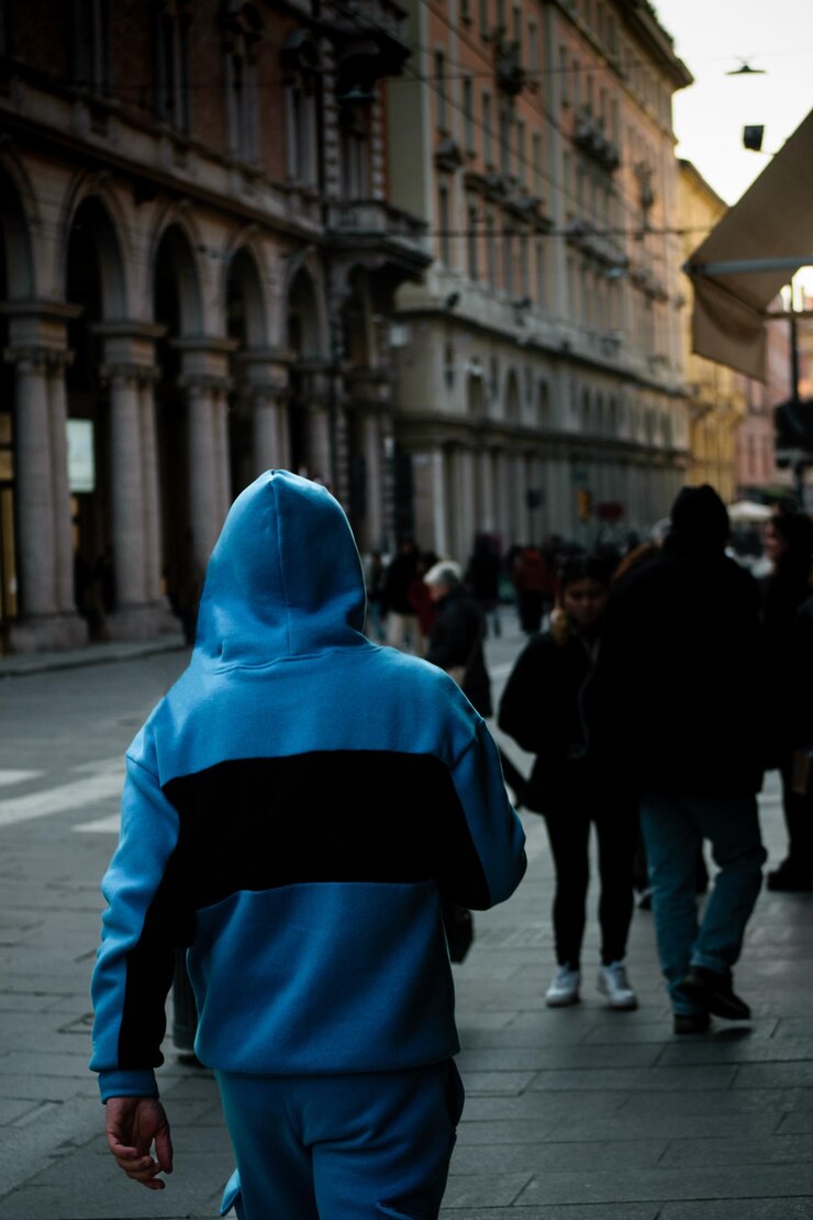Hombre elegante con capucha azul caminando por las calles de Bolonia