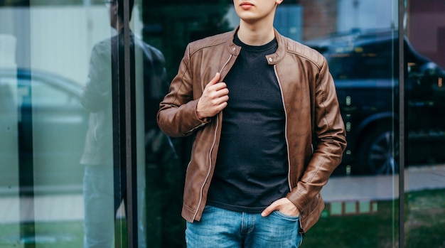 Un hombre elegante con chaqueta de cuero, gafas y camiseta negra. Foto de la calle