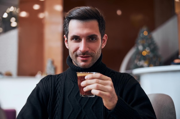 Hombre elegante feliz disfrutando de una bebida caliente en el hotel