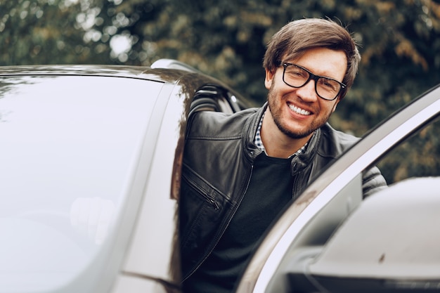 Hombre elegante con gafas se sienta en un coche