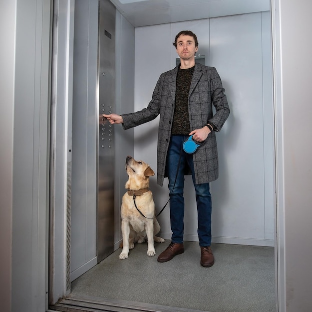 Hombre elegante guapo de pie con perro labrador en ascensor