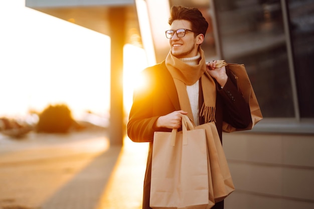 Hombre elegante con paquetes de papel después de ir de compras al atardecer