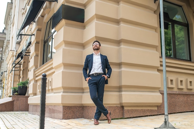 Hombre elegante parado cerca de la pared de un gran edificio