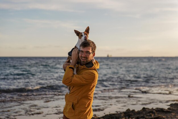 Hombre elegante paseando a su perro por el mar Cuidando animales