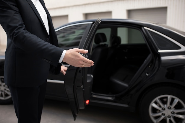 Hombre elegante de pie junto a su coche para servicios de taxi