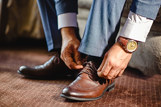 Un hombre elegante se pone zapatos negros, de cuero, formales.