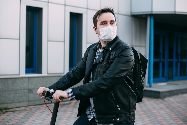 Hombre elegante con scooter eléctrico con máscara higiénica para prevenir infecciones