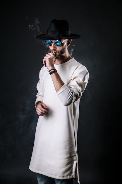 Hombre elegante con sombrero vaping