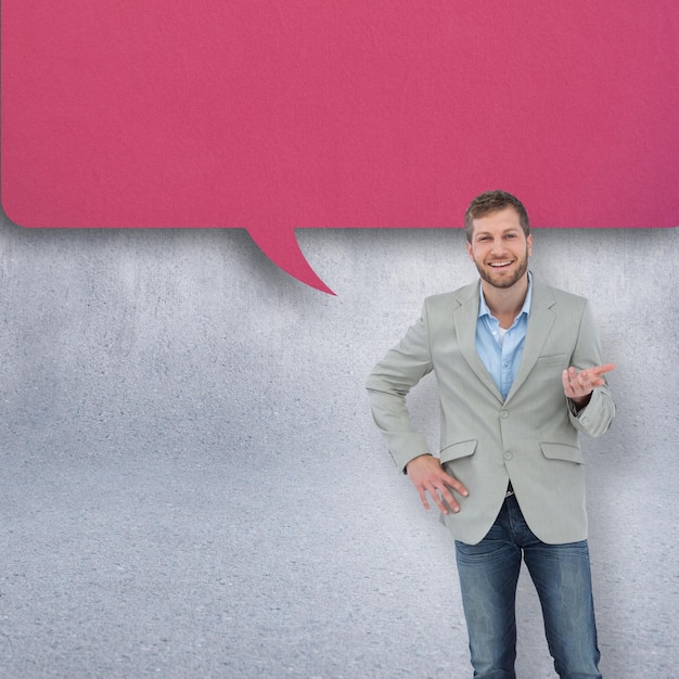 Hombre elegante sonriendo y gesticulando contra la pared gris con bocadillo