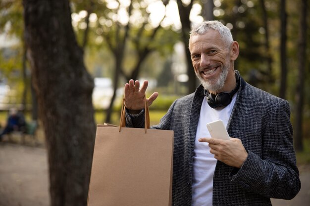 Foto hombre elegante sonriente con compras y smartphone