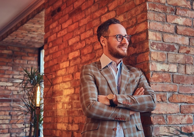 Hombre elegante con traje de franela y gafas con los brazos cruzados inclinados