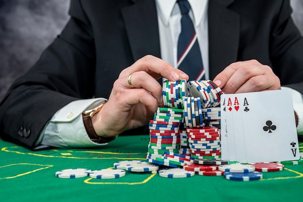 Hombre elegante en traje negro con cartas de juego y fichas de póquer en el concepto de juego de casino