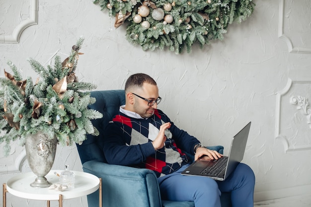 Hombre elegante usando laptop en Navidad.