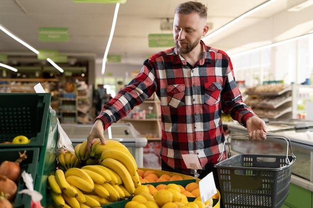 Un hombre elige frutas en el supermercado un hombre compra plátanos y verduras orgánicas un hombre elige productos de la tienda de comestibles