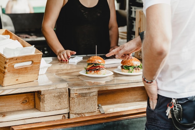 El hombre elige hamburguesas en una cena de fiesta de hamburguesas fiesta de comida de hamburguesas hamburguesa grande en las manos