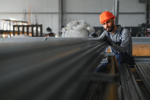 Foto hombre elige perfil de metal para la construcción en fábrica