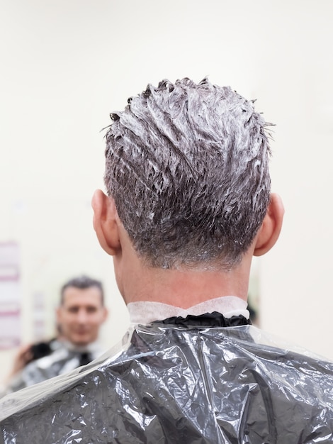 El hombre elige pintura para teñirse el cabello. Hombre tonificando su cabello.