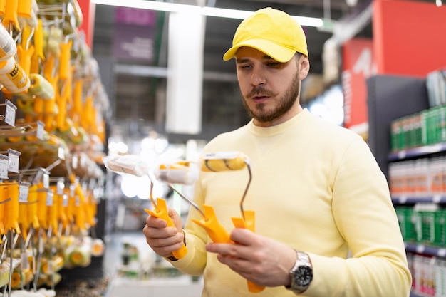 Un hombre elige un rodillo para pintar y reparar