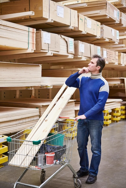 El hombre elige tableros para la construcción de la tienda.