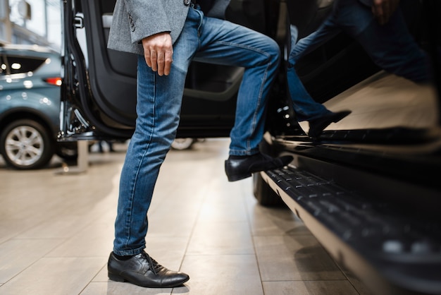 Hombre eligiendo camioneta en concesionario de automóviles. Cliente en la sala de exposición de vehículos, persona del sexo masculino que compra transporte, negocio de concesionario de automóviles