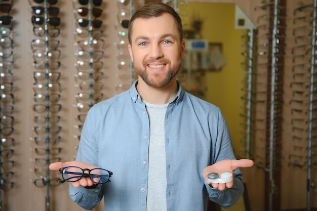 Foto el hombre está eligiendo gafas en la tienda de óptica.