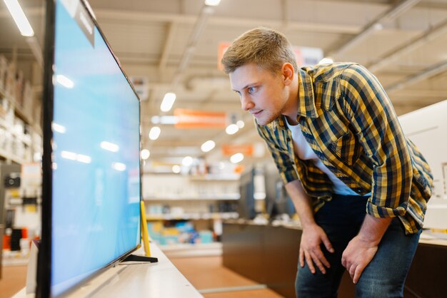 Hombre eligiendo TV de plasma en la tienda de electrónica