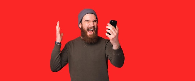 Hombre emocionado gritando fuerte mientras usa smartphone