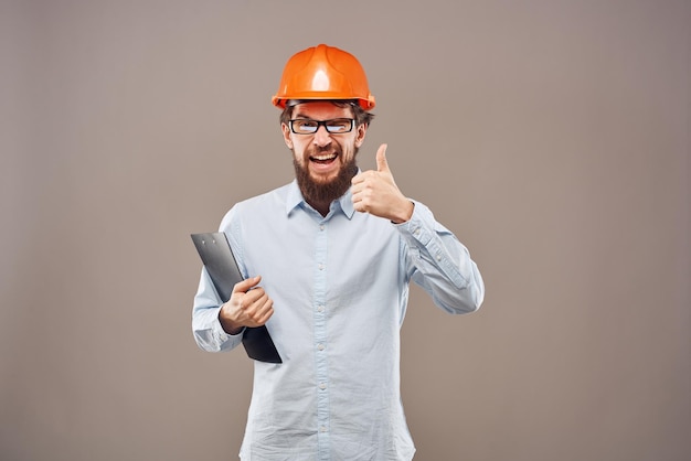 Hombre emocional con casco naranja en documentos de la industria Foto de alta calidad