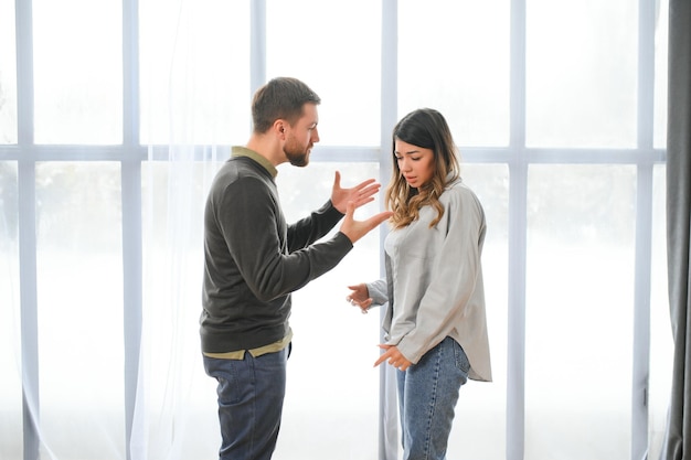 Foto hombre emocional gesticulando y gritando a su esposa pareja joven que tiene una pelea en casa concepto de abuso doméstico