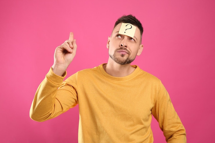Foto hombre emocional con signo de interrogación sobre fondo rosa
