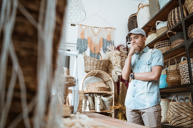 Hombre emprendedor con un gesto pensativo mientras está de pie en una tienda de artesanía