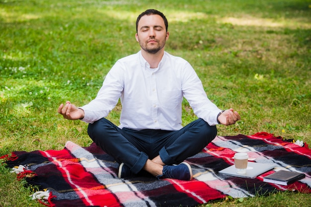 Hombre empresario meditando al aire libre en postura de loto