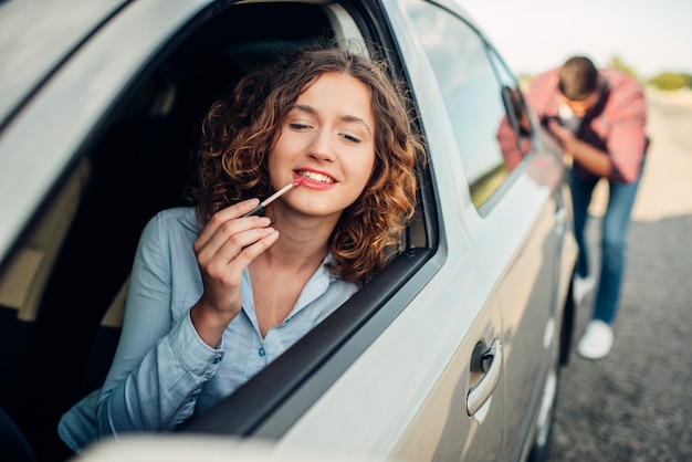 Foto hombre empujando un coche roto, mujer conductora