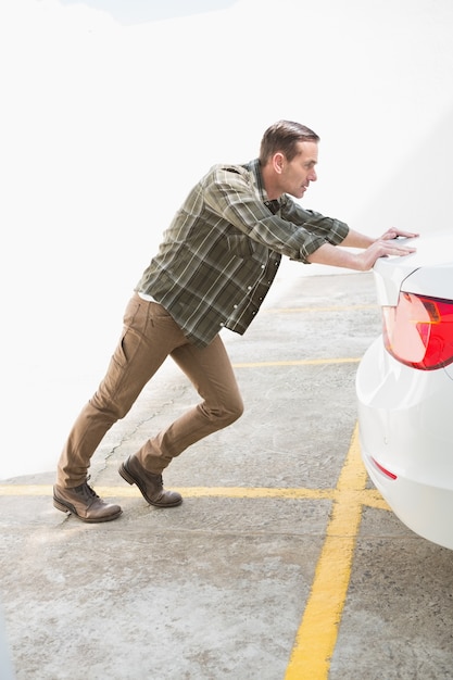 Foto hombre empujando su coche averiado