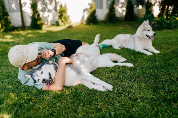 Un hombre encantador y dos perros posando sobre la hierba