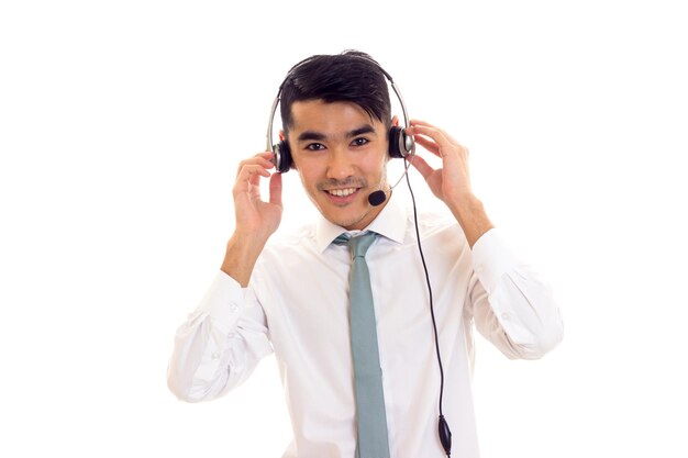 Hombre encantador joven con cabello oscuro en camisa blanca con corbata azul con auriculares en estudio