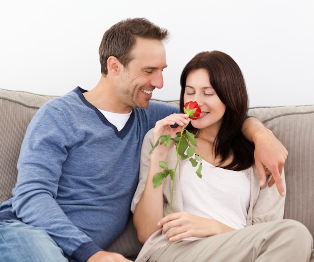 Hombre encantador mirando a su novia que huele una rosa roja