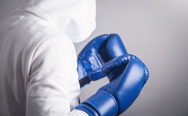 Hombre encapuchado con guantes de boxeo.