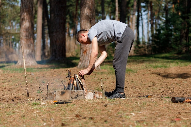 Un hombre enciende un fuego. vacaciones familiares en la naturaleza