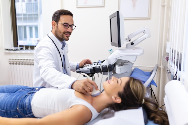 Hombre endocrinólogo haciendo ultrasonografía a una paciente en una oficina de ultrasonido Diagnóstico por ultrasonido de la glándula tiroides