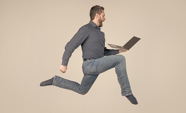 Hombre enérgico sorprendido corriendo mientras trabaja en línea en una computadora portátil apúrate para ir de compras