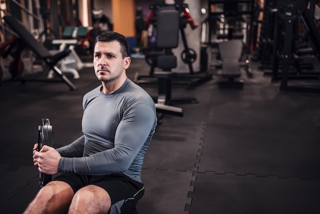 Hombre enfocado en ropa deportiva entrenando abdominales con pesas.