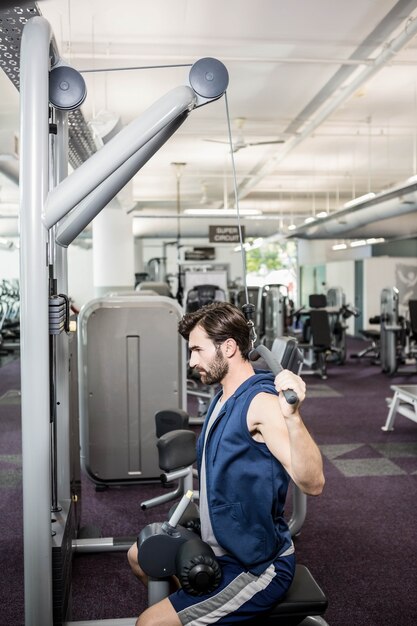 Hombre enfocado usando máquinas de pesas para brazos en el gimnasio