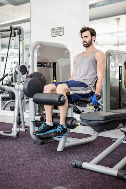 Hombre enfocado usando máquinas de pesas para piernas en el gimnasio