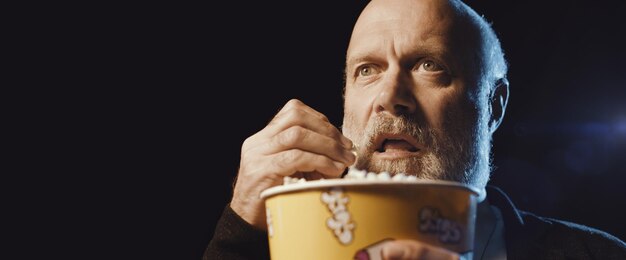 Hombre enfocado viendo una película de suspenso en el cine