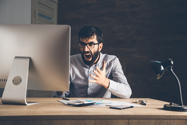 Hombre enojado con computadora en el escritorio