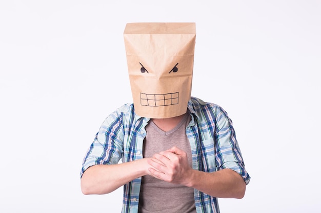 Hombre enojado en la perforación de máscara de bolsa de papel, él está apretando los puños